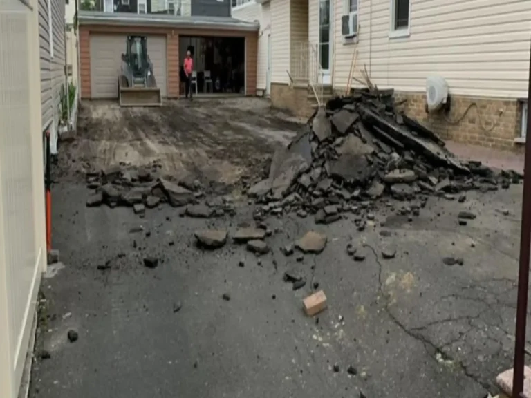 Old asphalt driveway torn out before repaving between two houses