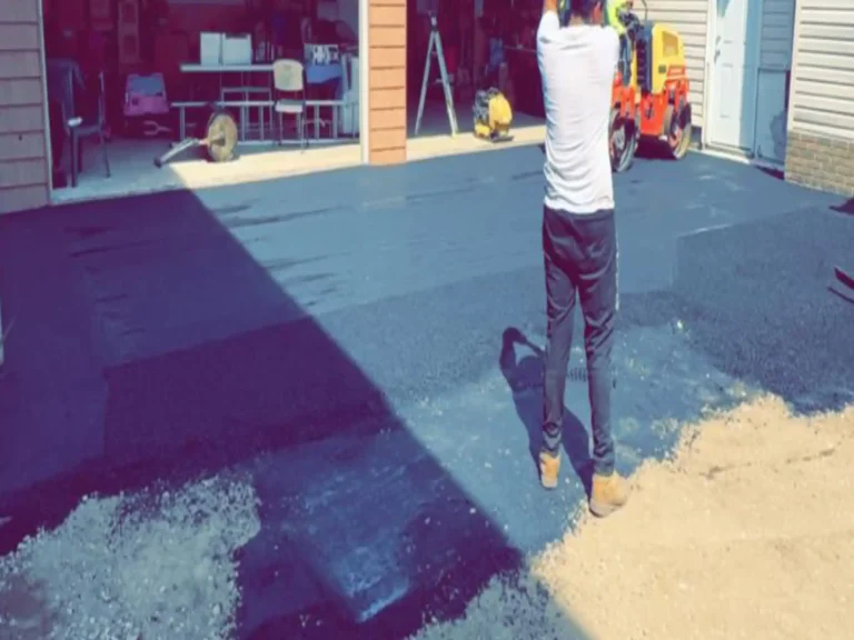Crew member spreading fresh asphalt on a driveway