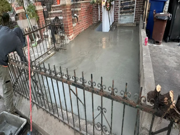 Freshly poured concrete in front of a brick home while the crew finishes the surface