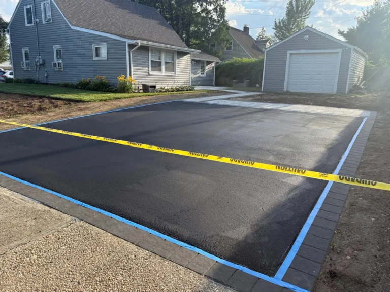 New asphalt driveway with a dark paver border next to a garage